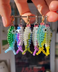 a person is holding some tiny beads in front of their earrings that look like seahorses