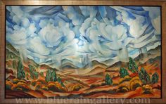 a painting on display in a wooden frame with clouds above the mountains and trees below