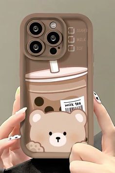 a woman holding up her phone case with a bear on the side and a drink in it