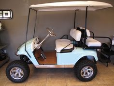 a blue and white golf cart parked in a room next to a shelf with items on it