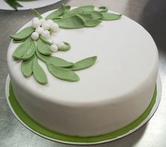 a white cake with green leaves and berries on it