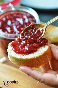 a person holding a spoon over a piece of bread with jam on it