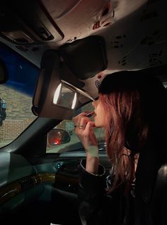 a woman sitting in the back seat of a car talking on her cell phone while driving