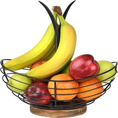 a metal bowl filled with fruit on top of a wooden table