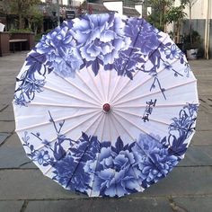 an umbrella with blue flowers on it is sitting on the ground in front of a building