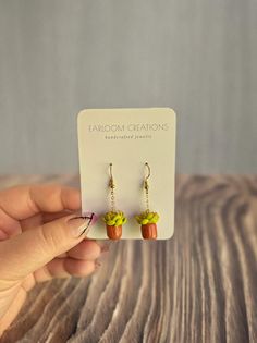 a pair of earrings with acrylic designs on them sitting on top of a wooden table