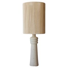 a white table lamp with a beige shade on it's side and a wooden base