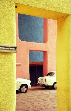 two white trucks parked in front of a pink and blue building