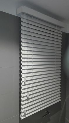 a bathroom with a toilet, sink and window blinds in the shades on the wall