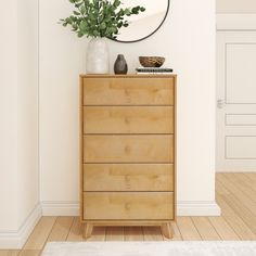 a wooden dresser sitting in front of a white wall with a round mirror above it