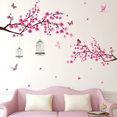 a pink couch sitting under a tree with birds flying over it and a birdcage hanging from the branch