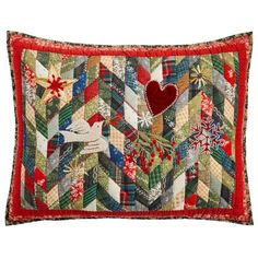 a red and green patchwork pillow with a heart on the front, surrounded by snowflakes