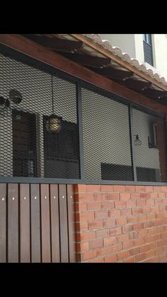 a brick building with two windows and a metal screen on the outside wall that is closed