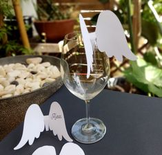 a wine glass with angel cutouts sitting on a table in front of some rocks