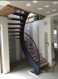 a spiral staircase in the middle of a room with white walls and flooring on it