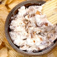 a bowl full of potato chips with a wooden spoon sticking out of the dip in it