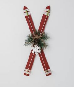 two red skis tied up to each other with snowflakes and evergreen branches