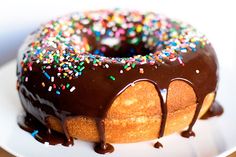 a donut with chocolate glaze and sprinkles on it sitting on a plate