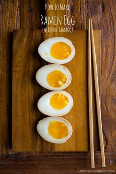 three hard boiled eggs on a cutting board with chopsticks