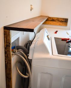 a washer and dryer in a room with some wood on the shelf above them