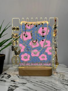 a display case with necklaces on it and a potted plant in the background