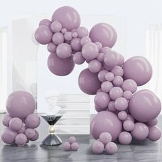 purple balloons are floating in the air near a hourglass and other items on a table