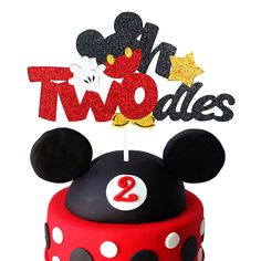 a mickey mouse cake with two candles on top and the number two in red, white, and black