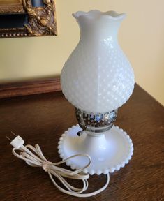 a white glass vase sitting on top of a wooden table next to a charger