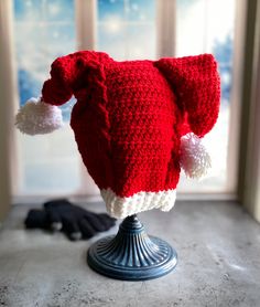 a red and white knitted hat on top of a metal stand