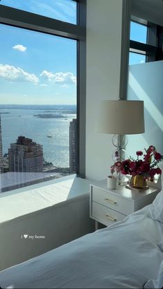 a bedroom with a large window overlooking the water and cityscape in the background