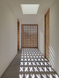 an empty room with light coming in through the window and shadows on the wall behind it