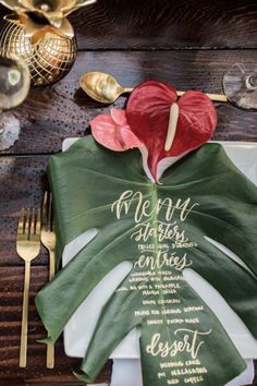 a place setting with napkins and gold utensils on a wooden table top