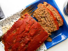 a blue plate topped with meatloaf next to a slice of bread covered in sauce