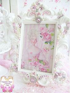 an ornate white frame with pink flowers and pearls on the edges is next to a cake