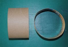 a roll of toilet paper next to an empty roll of tape on a green surface