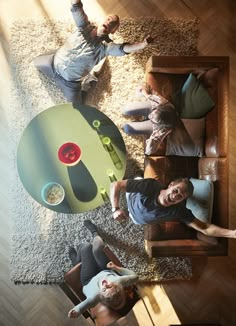 three people sitting at a table with their feet on the coffee table and one person laying down