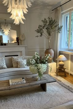 a living room filled with furniture and a fire place under a chandelier hanging from the ceiling