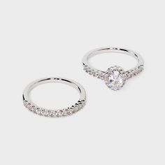 two white gold rings with diamonds on each one and an oval shaped diamond in the middle