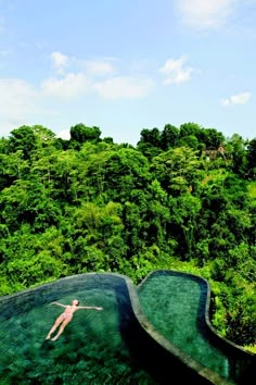 a person jumping into a pool in the middle of trees