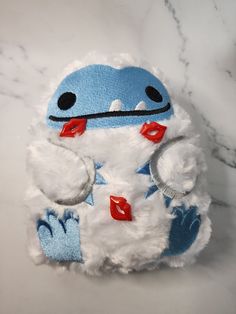 a blue and white stuffed animal sitting on top of a marble counter next to a cell phone