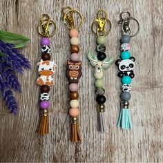 four keychains with different designs and animals on them sitting next to a purple flower