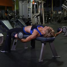 a woman laying on top of a bench in a gym