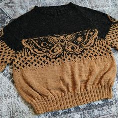 a sweater with an owl design on it sitting on top of a carpeted floor