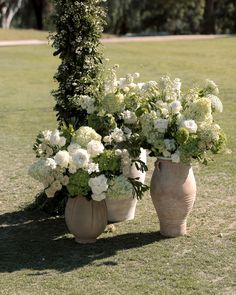 two vases with flowers are sitting in the grass