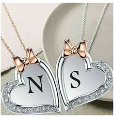 two heart shaped necklaces with bows on them and the letter s in the middle