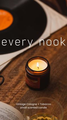 a candle sitting on top of a wooden table next to an open book and record