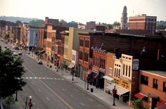 an empty city street lined with buildings and cars parked on the side of the road