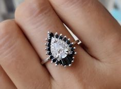 a close up of a person's hand holding an engagement ring with a black and white diamond