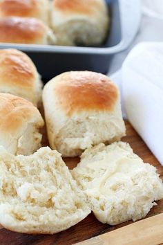 rolls are cut in half on a cutting board next to a loaf of bread and a baking pan