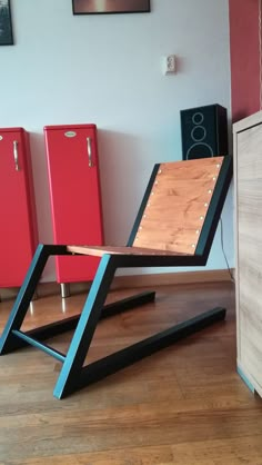 a wooden chair sitting on top of a hard wood floor next to red refrigerators